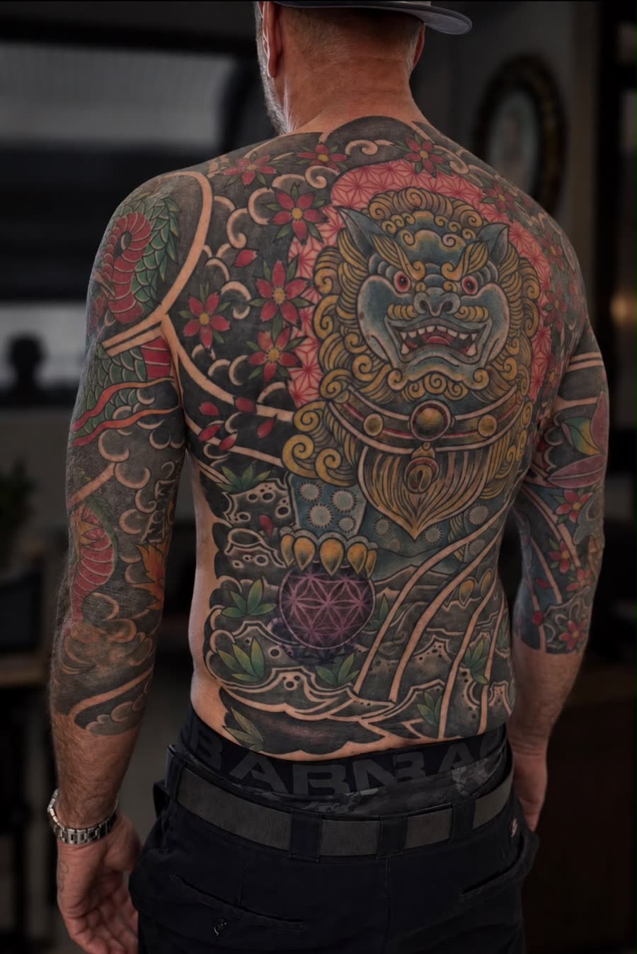 Farbiges Rückenstück mit Shishi-Löwe, Blüten und Wellen – Tattoo aus Bad Bramstedt